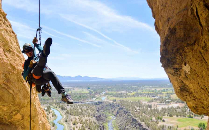 a rock climber is suspended in the air between two rock walls by a rope and harness